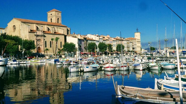 A marina with numerous boats docked, a historic building with a tower, and a clear blue sky. - Large T2 in villa with sea view and spa not overlooked (La Ciotat)