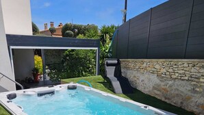 A rectangular hot tub with a stone wall and a grassy area around it. - Large T2 in villa with sea view and spa not overlooked (La Ciotat)
