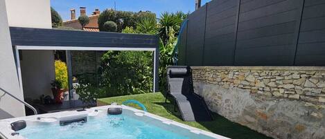 A rectangular hot tub with a stone wall and a grassy area around it.