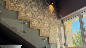 Una escalera moderna con un revestimiento de pared estampado, un jarrón grande y una vista por una ventana.