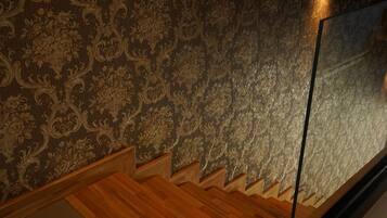 Eine Treppe mit Holzdielen und einer Wand mit aufwendiger Blumen-Tapete.