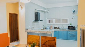 A compact kitchen with blue cabinets, a white countertop, a built-in oven, and a microwave.