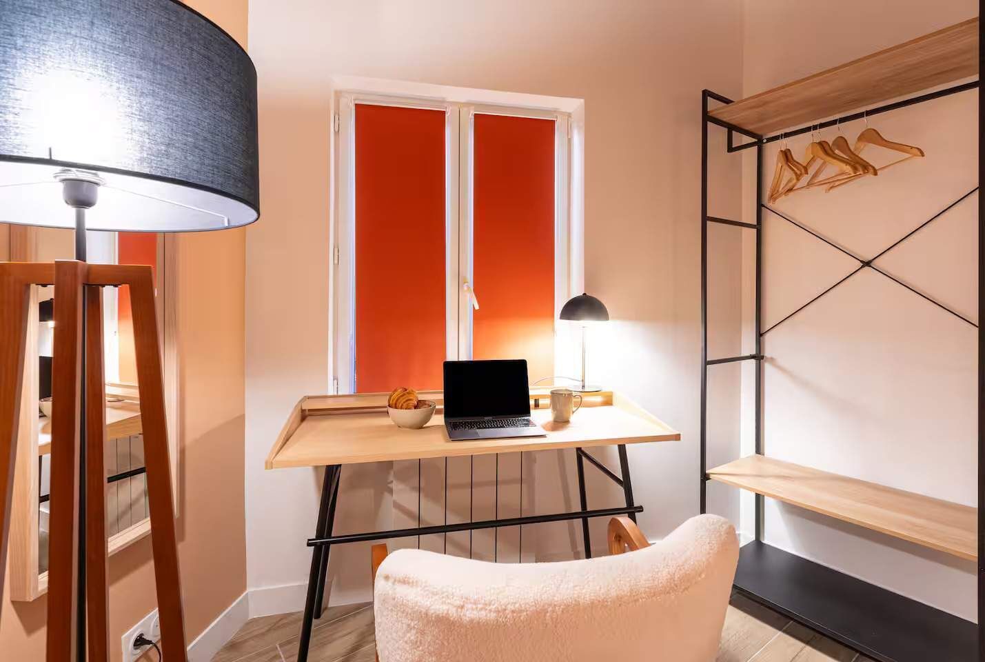 Une petite pièce comprenant un bureau, un ordinateur portable, une lampe et une chaise.