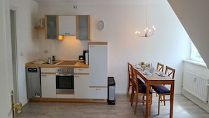 Una cocina compacta con lavavajillas, horno y una mesa de comedor con sillas.