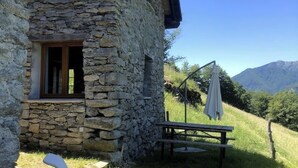 A stone building with a window, a picnic table, and an umbrella. - Idyllic country house in Rasa - Centovalli (Centovalli)