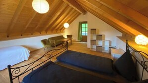 A cozy attic bedroom with a sloped ceiling, a bed, a sofa, a table, and a bookshelf. - Idyllic country house in Rasa - Centovalli (Centovalli)