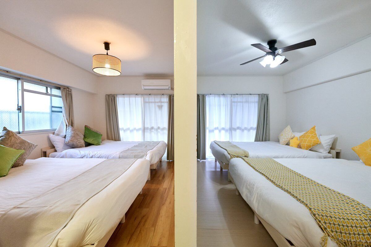 Ein Hotelzimmer mit zwei Betten, einem Deckenventilator und einem Fenster mit Vorhängen.