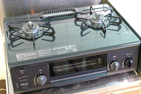 Une cuisinière dotée de deux brûleurs, d’un panneau de commande et d’une grille de ventilation.