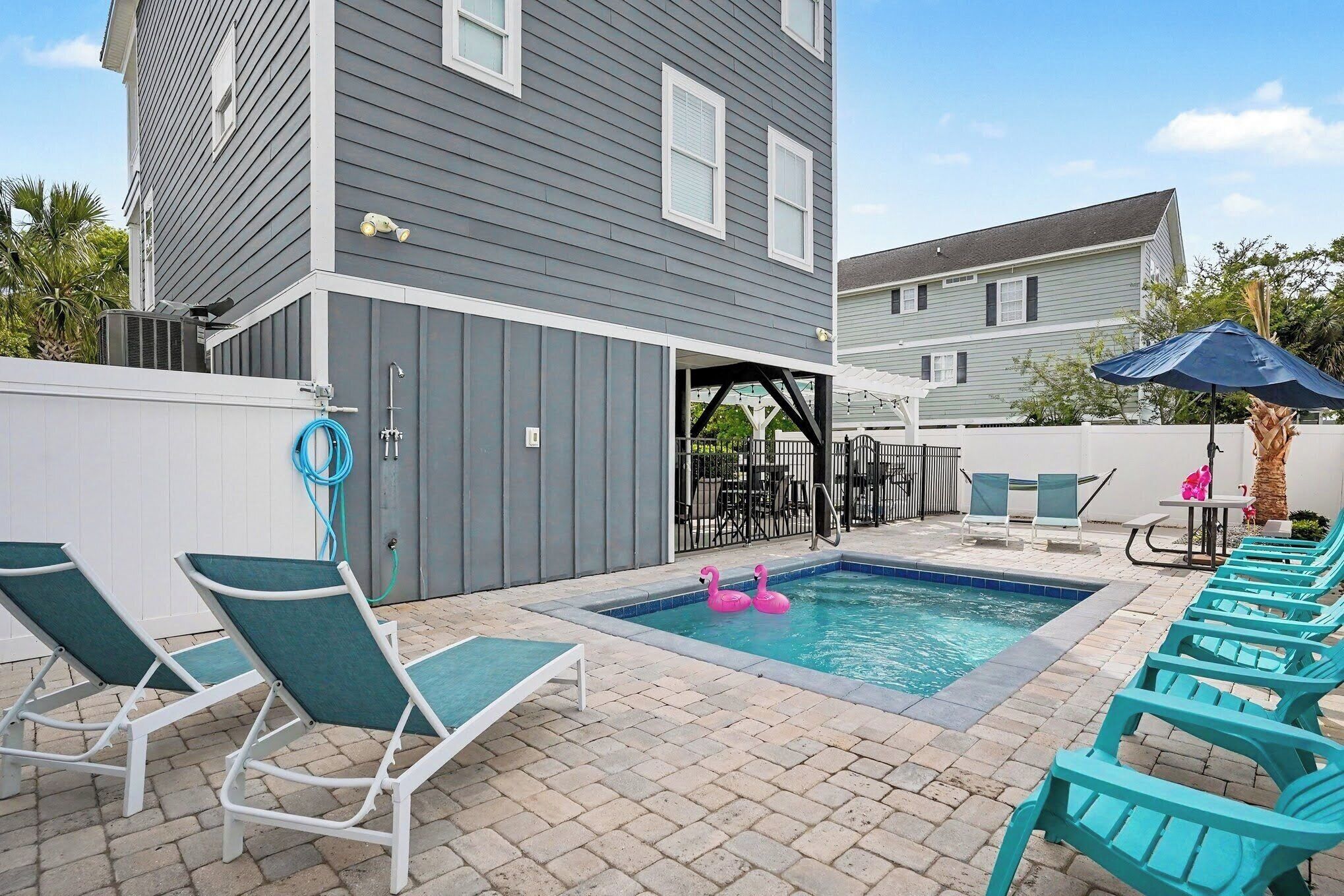 A backyard with a swimming pool, lounge chairs, and a patio area.