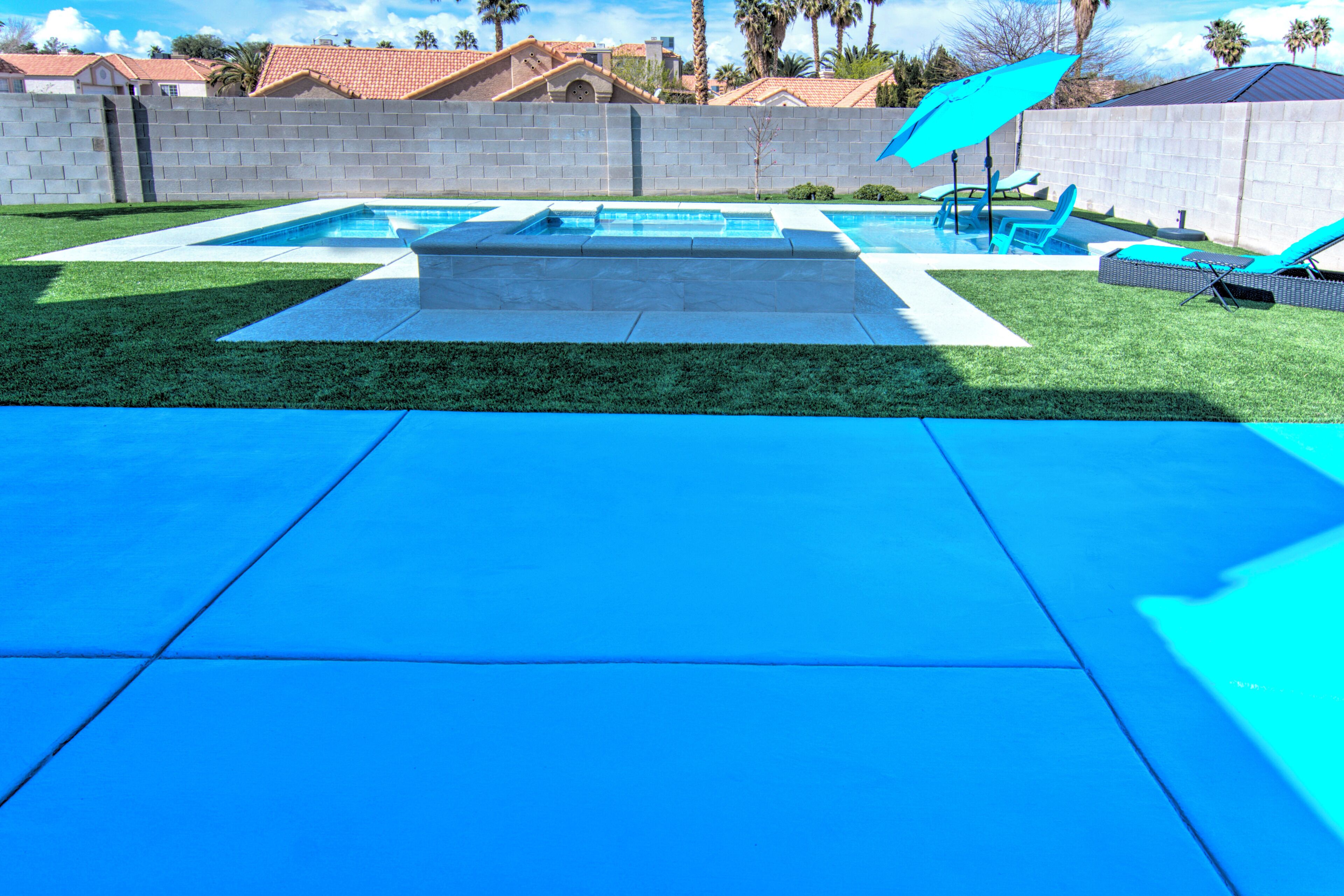 A backyard with a swimming pool, a patio area, and a brick wall.