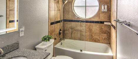 A bathroom with a bathtub, toilet, sink, and a mirror.