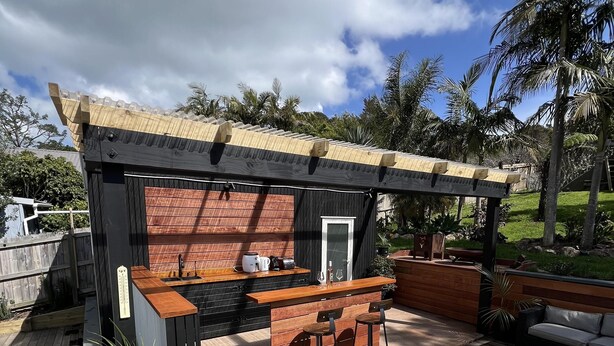 A wooden deck with a hot tub, a bar area, and a pergola. - La Maison Soleil - Modern, sun-filled home with 4 bedrooms (2 kings including a stand-alone sleepout in the pool area, 2 queens) and 3 tiled bathrooms. Features a full kitchen, aircon, and open living flowing to a large garden with BBQ, heated swim s (Waiheke Island)