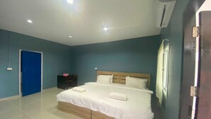 Un dormitorio con una cama grande, una puerta azul, una mesita y una ventana.