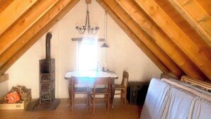 A cozy attic room with a wooden ceiling, a central table with chairs, a fireplace, and a sofa. - Rustic Monti - Rasa - Centovalli (Centovalli)