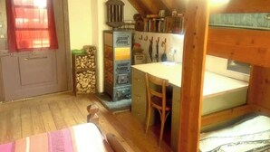A compact room with a bed, a small desk, and a stove. - Rustic Monti - Rasa - Centovalli (Centovalli)