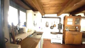 A rustic kitchen with wooden beams, a sink, stove, and cabinets. - Rustic Monti - Rasa - Centovalli (Centovalli)