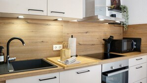 Una cocina moderna con encimera de madera, pileta negra y electrodomésticos de acero inoxidable.