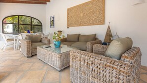 A cozy living area with wicker furniture, a glass coffee table, and a decorative wall piece. - Hibiscus by Sun & Sea Homes (Calpe)