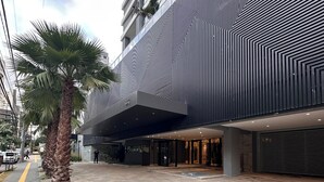 A modern building with a geometric facade, a covered entrance, and a palm tree in the foreground. - 2 Suites Setor Bueno & Vaca Brava Hop Amparo (Goiânia)
