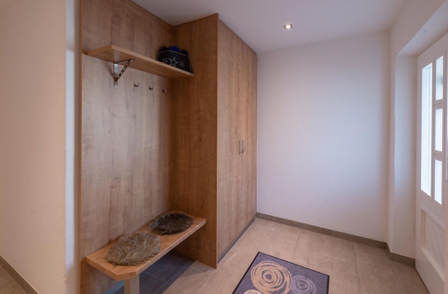 Un pasillo con un banco de madera, un estante con una bolsa de estampado de estrellas y una puerta con manija.