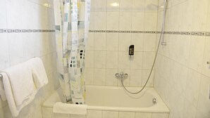 Un área de ducha con puerta de vidrio, un cabezal de ducha manual y un panel de control.