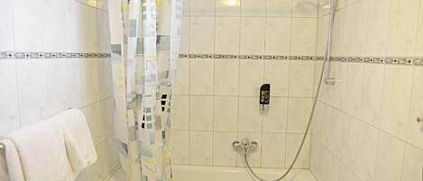 Un área de ducha con puerta de vidrio, un cabezal de ducha manual y un panel de control.