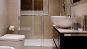 Et moderne badeværelse med toilet, bidet og en stor vask.