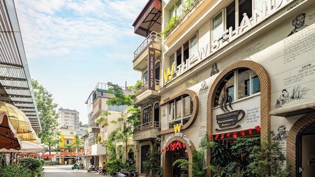 A street with a cafe named "The Wiselands Coffee" with outdoor seating and potted plants.