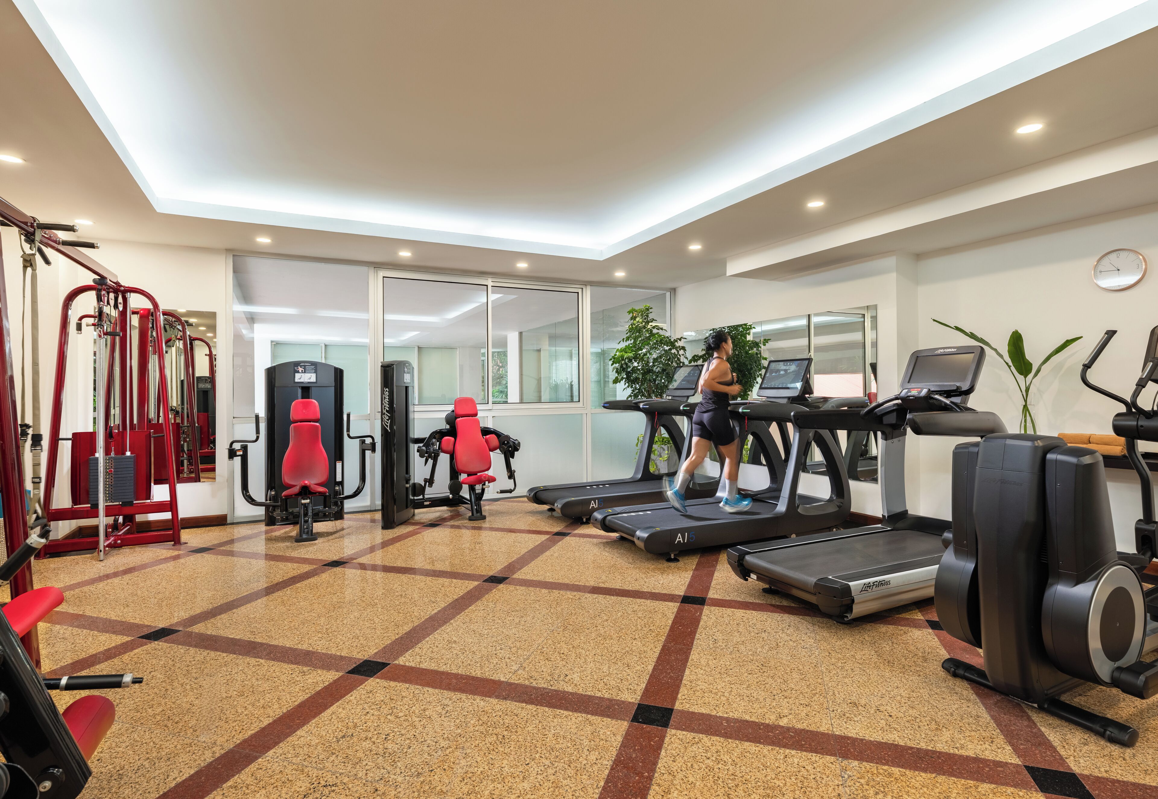 A gym with treadmills, exercise machines, and a mirrored wall.