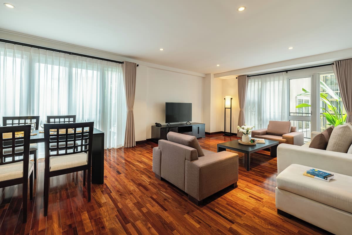 A spacious living room with a wooden floor, a dining area with a table and chairs, and a seating area with sofas and a coffee table.