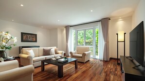 A modern living room with a sofa, armchairs, a coffee table, and a TV.