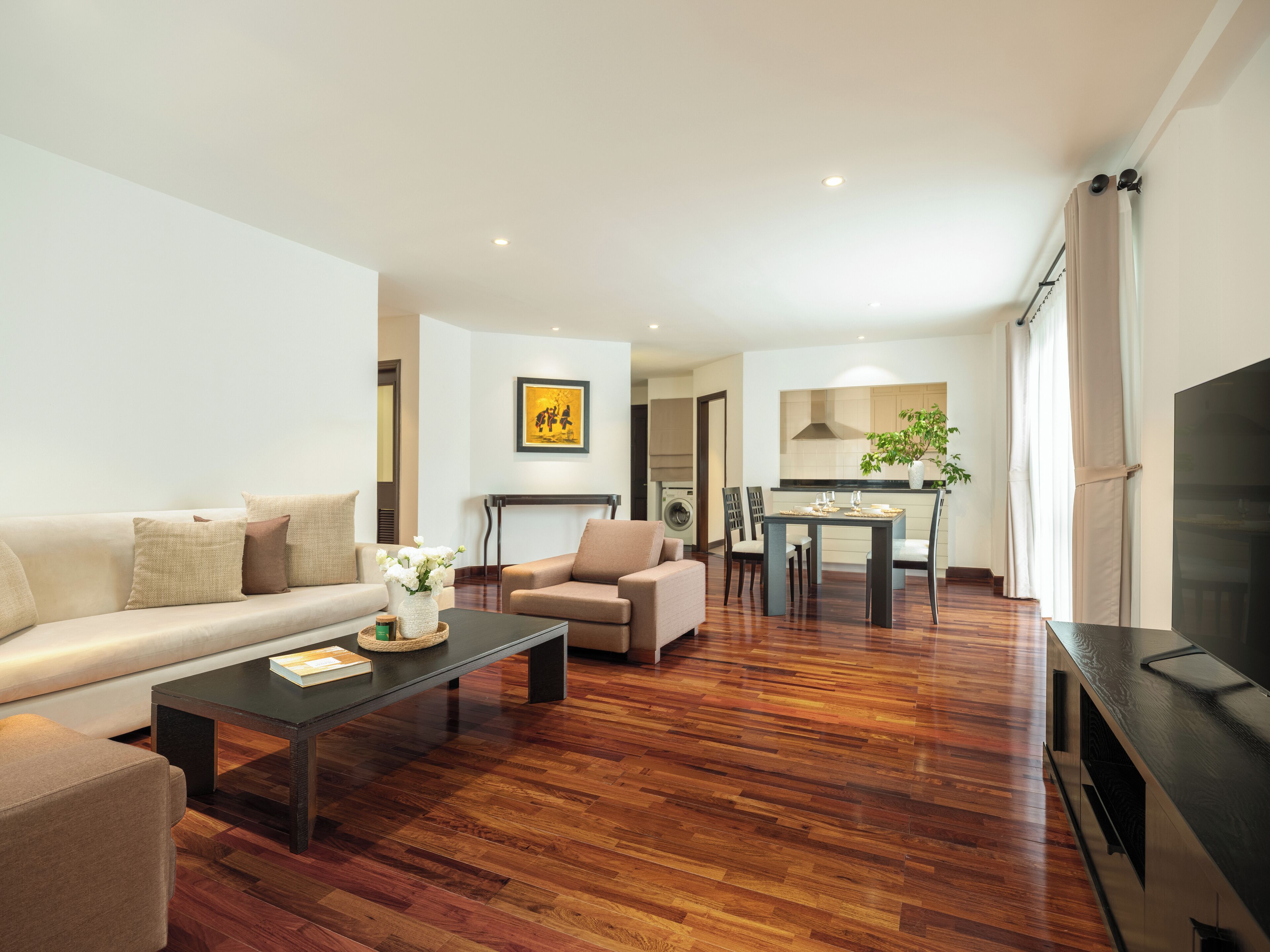 A modern living room with a sofa, coffee table, and a dining area with chairs and a table.