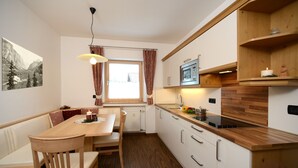 Una cocina compacta con una mesa de madera, sillas, un microondas y un lavamanos.