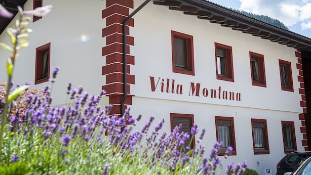 Villa Montana con fachada blanca, marcos de ventana rojos y cielo despejado.