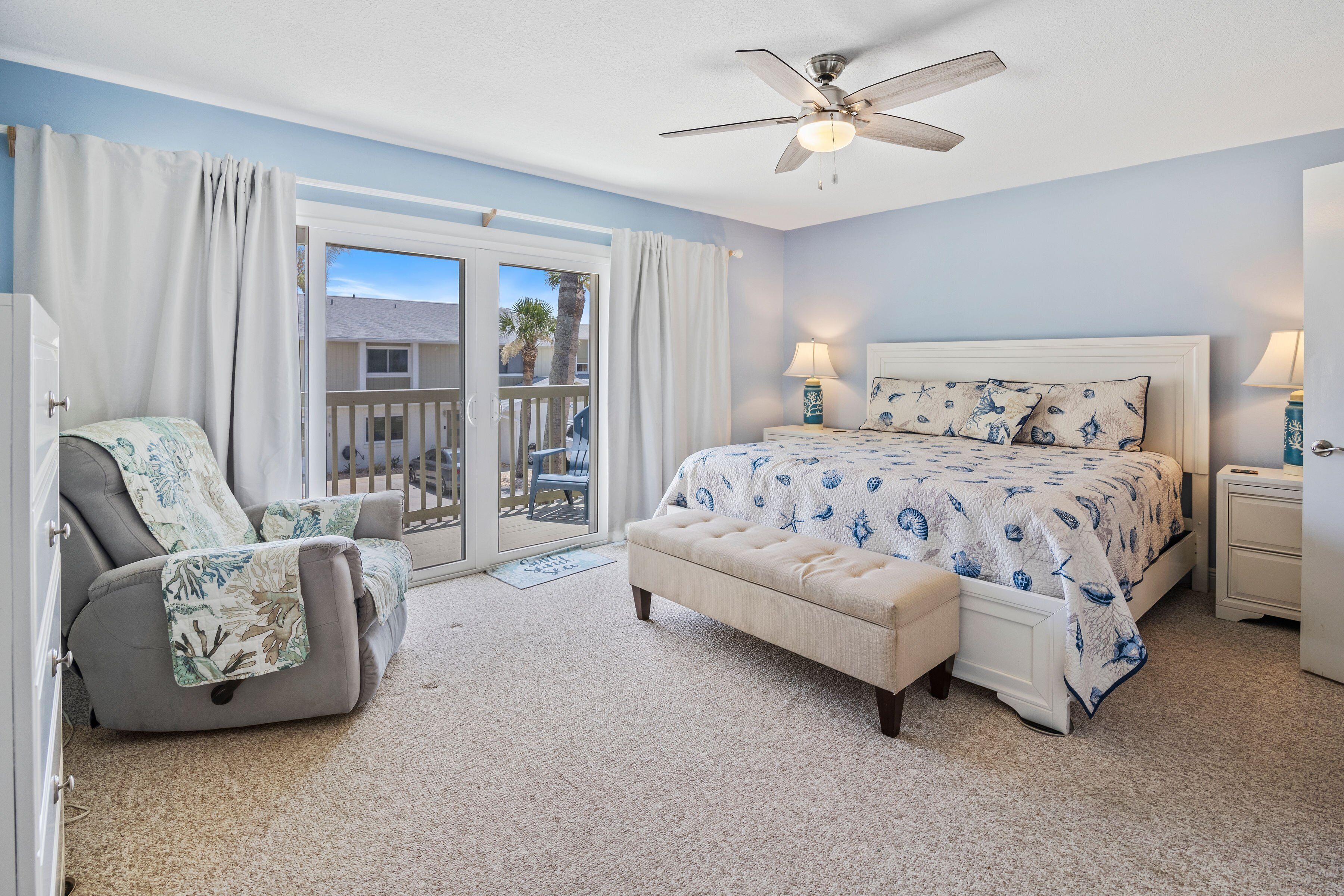 Unwind in this spacious master suite featuring coastal décor, a plush king bed, and private balcony access—perfect for enjoying the ocean breeze after a day at the beach.