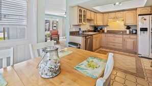 A kitchen with wooden cabinets, a refrigerator, and a dining table with chairs.