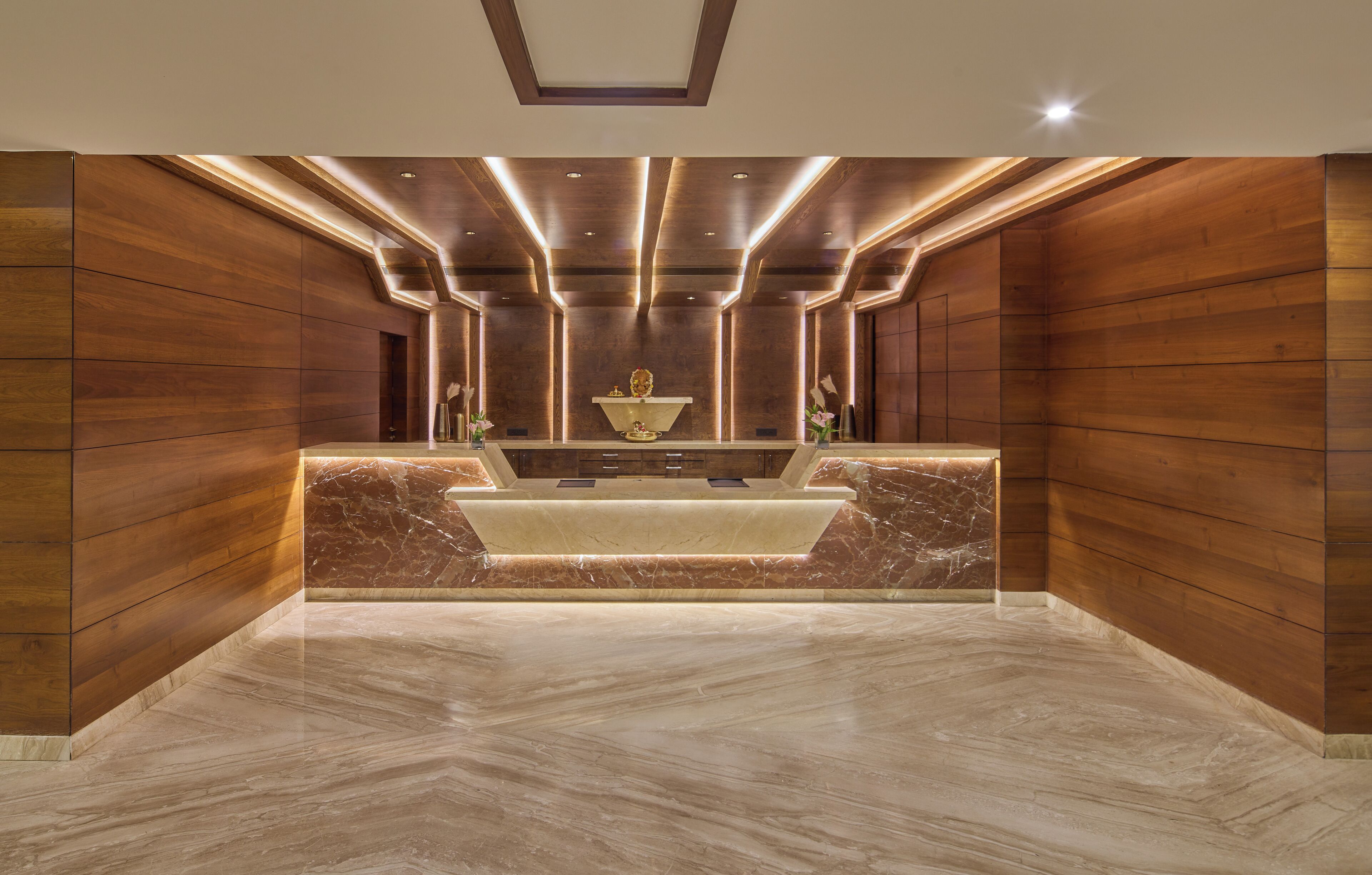 A reception area with a marble counter, wooden paneling, and recessed lighting.