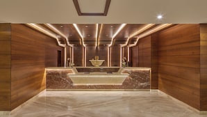 A reception area with a marble counter, wooden paneling, and recessed lighting. - Regenta Hubbali (Hubli)