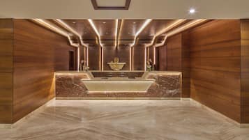 A reception area with a marble counter, wooden paneling, and recessed lighting.