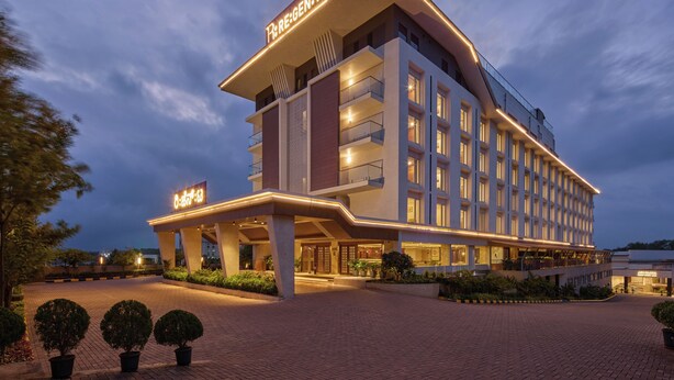 A modern hotel with a prominent sign, multiple balconies, and a well-lit entrance. - Regenta Hubbali (Hubli)