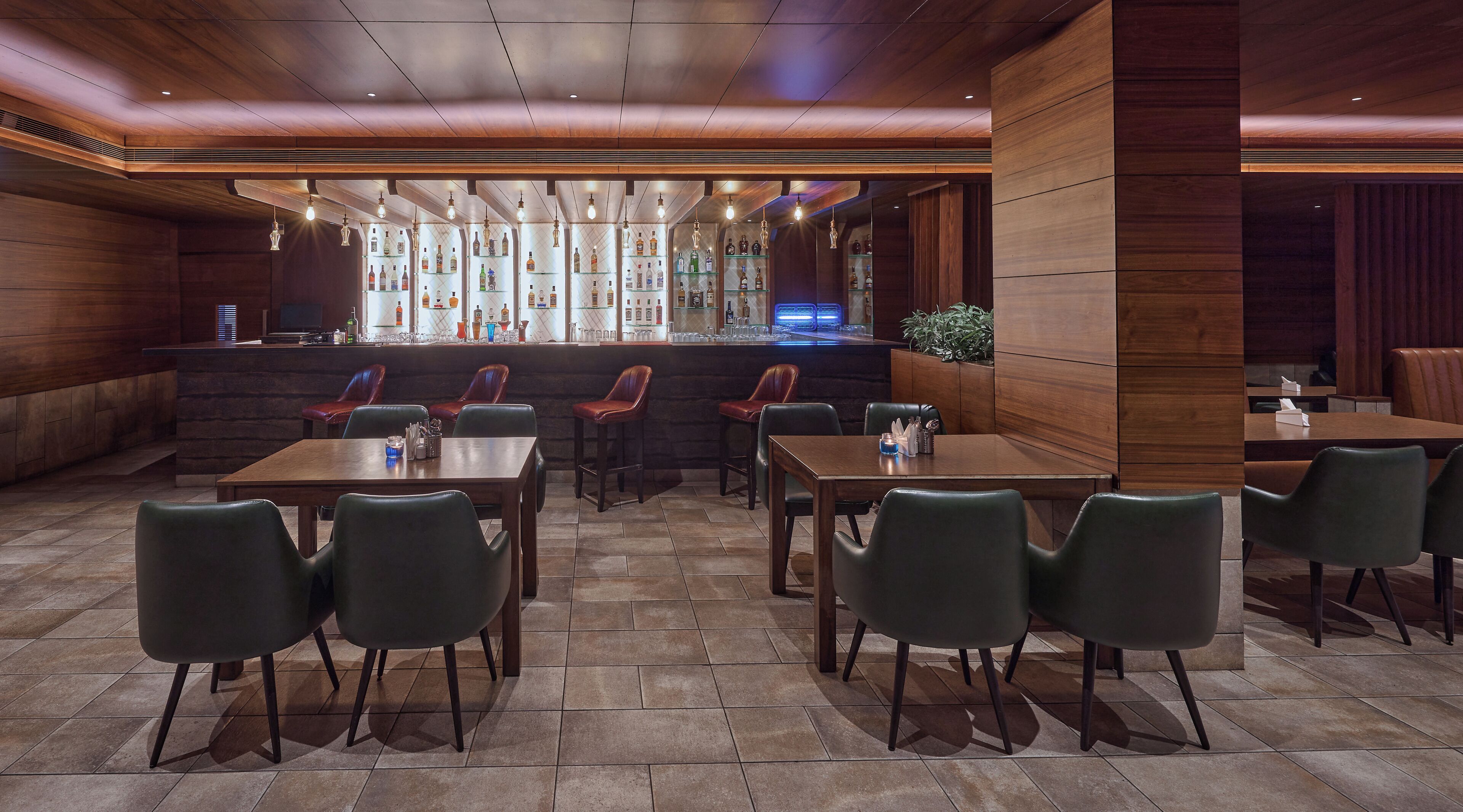 A restaurant with a bar area, multiple seating options including tables and chairs, and a tiled floor.