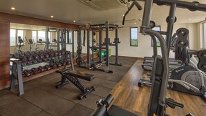 Un gimnasio con equipos de ejercicio variados, incluyendo cintas de correr, máquinas de pesas y pesas libres.