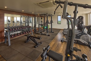 Un gimnasio con equipos de ejercicio variados, incluyendo cintas de correr, máquinas de pesas y pesas libres.