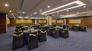 Un salón de conferencias con varias mesas redondas, cada una con sillas y centros de mesa.