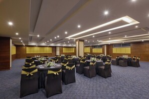 Un salón de conferencias con varias mesas redondas, cada una con sillas y centros de mesa.