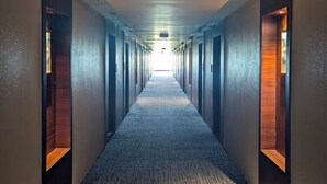 A long, narrow hotel corridor with carpeted floors and doors on both sides. - Regenta Hubbali (Hubli)