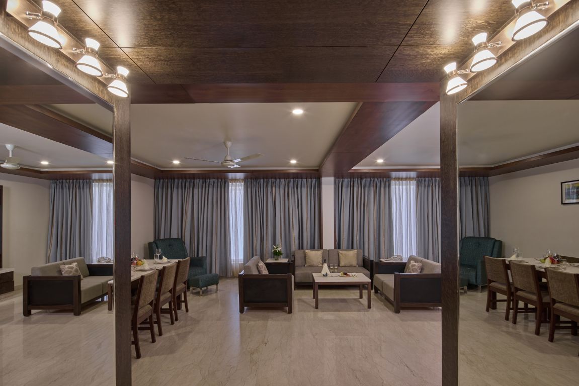 Uma sala de estar ampla, com mesa de jantar, sofás e ventilador de teto.