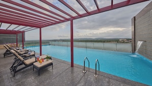 A rooftop pool with lounge chairs and a view of the landscape. - Regenta Hubbali (Hubli)