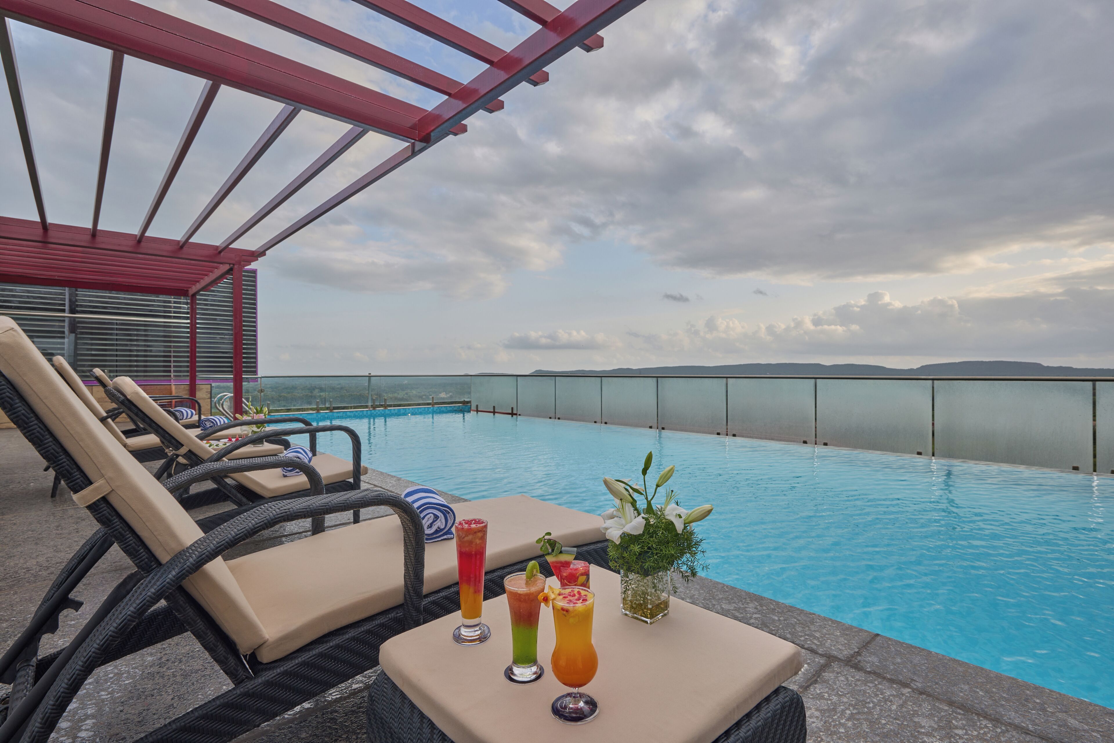 A rooftop pool area with lounge chairs and a glass balustrade.