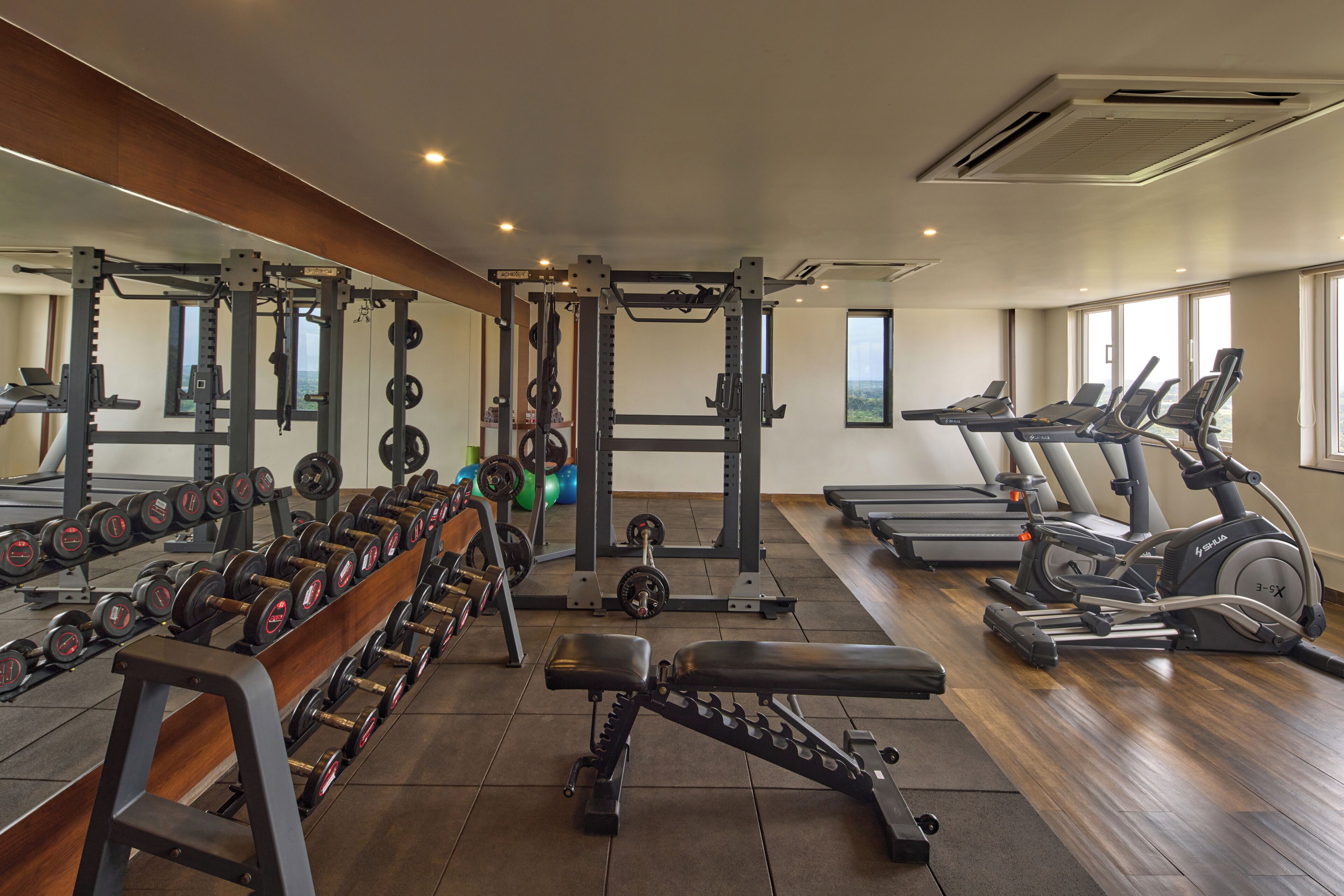 A gym with weightlifting equipment, treadmills, and a bench.
